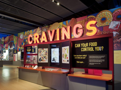 A photo of Science Museum's Cravings exhibit. It is designed to look like a sweet shop or factory, with a sign that says: "Can your food control you?"