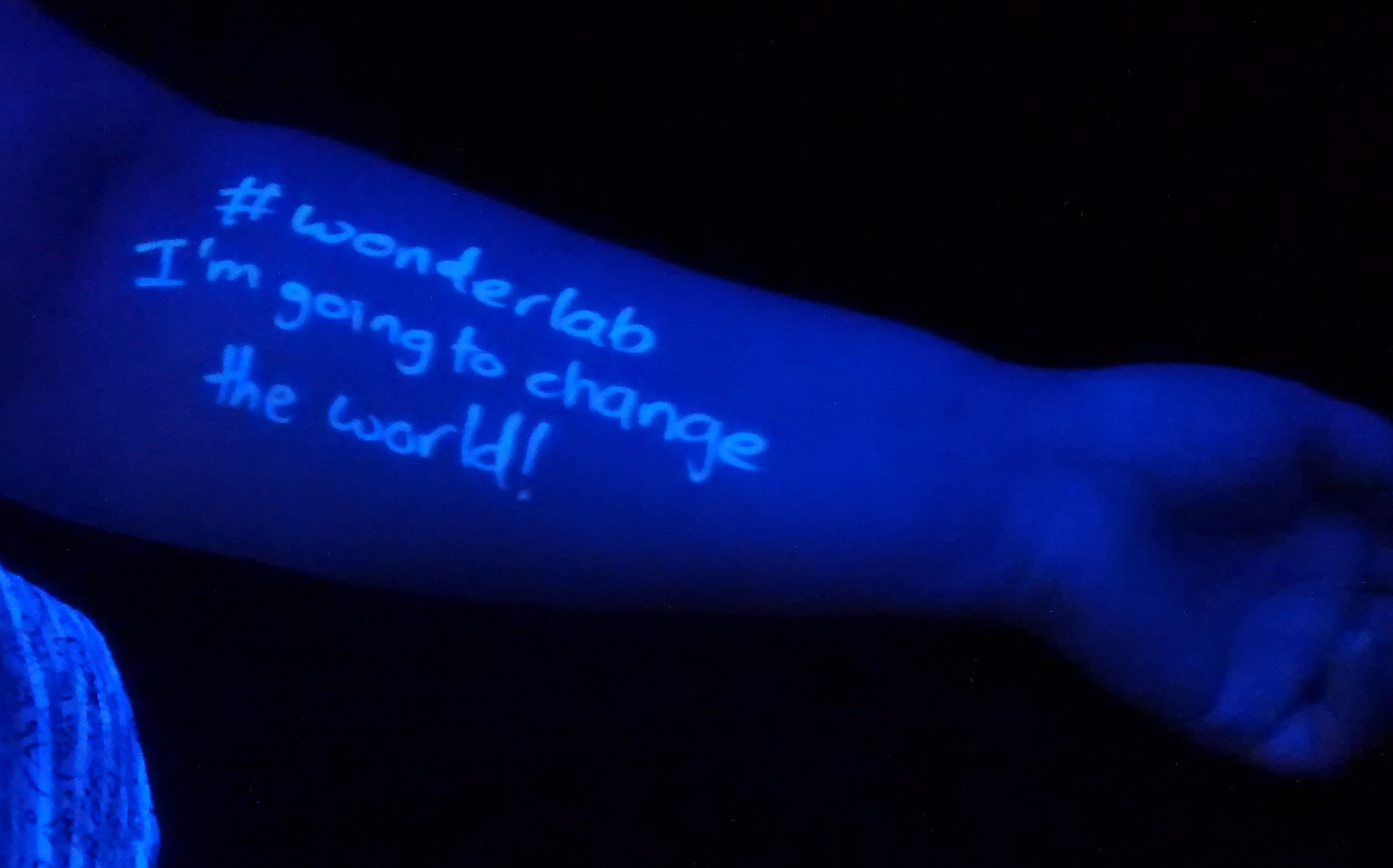 Positive message written in UV on a visitors arm saying '#wonderlab I'm going to change the world!'