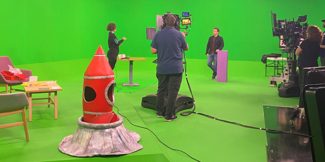 An Explainer being filmed in front of a green screen demoing one of our hands-on activities with Mark Rhodes in the BBC studios.