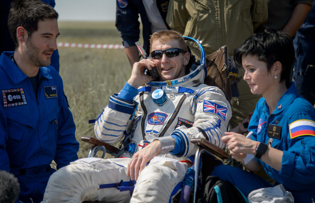Tim Peake of the European Space Agency talks on a satellite phone in a chair outside the Soyuz TMA-19M spacecraft just minutes after he and Yuri Malenchenko of Roscosmos and Tim Kopra of NASA landed in a remote area near the town of Zhezkazgan, Kazakhstan on Saturday, June 18, 2016. Kopra, Peake, and Malenchenko are returning after six months in space where they served as members of the Expedition 46 and 47 crews onboard the International Space Station. Photo Credit: (NASA/Bill Ingalls)