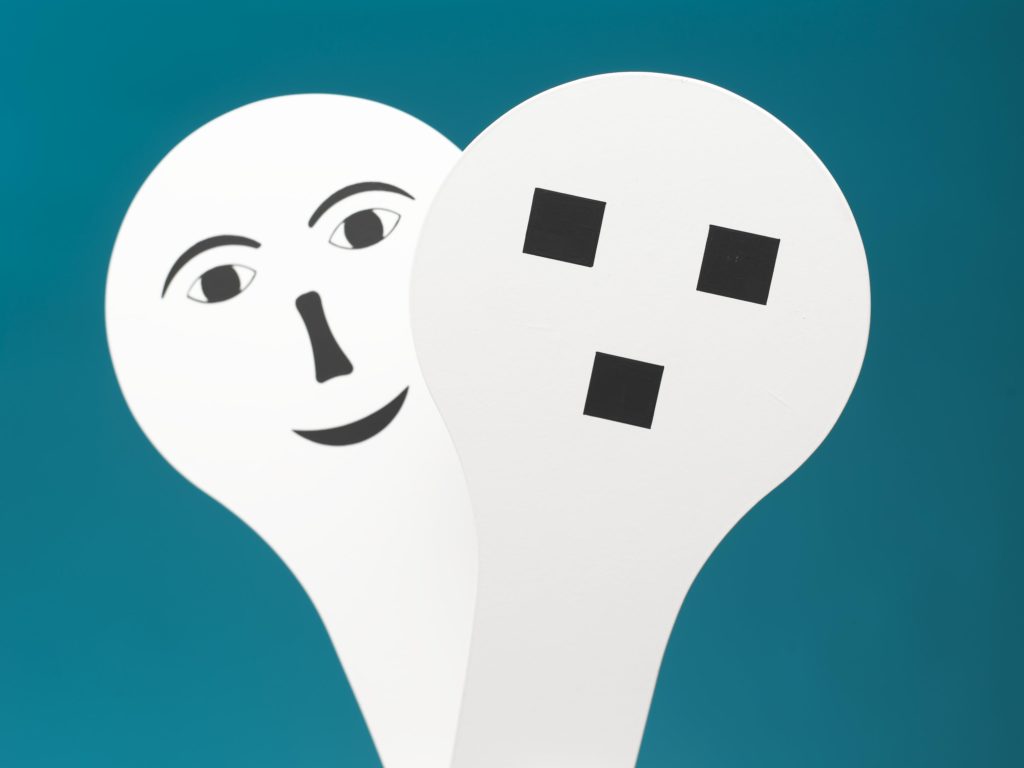An illustration of two white face paddles. One shows a clearly defined humanoid face, the other is much more abstract.